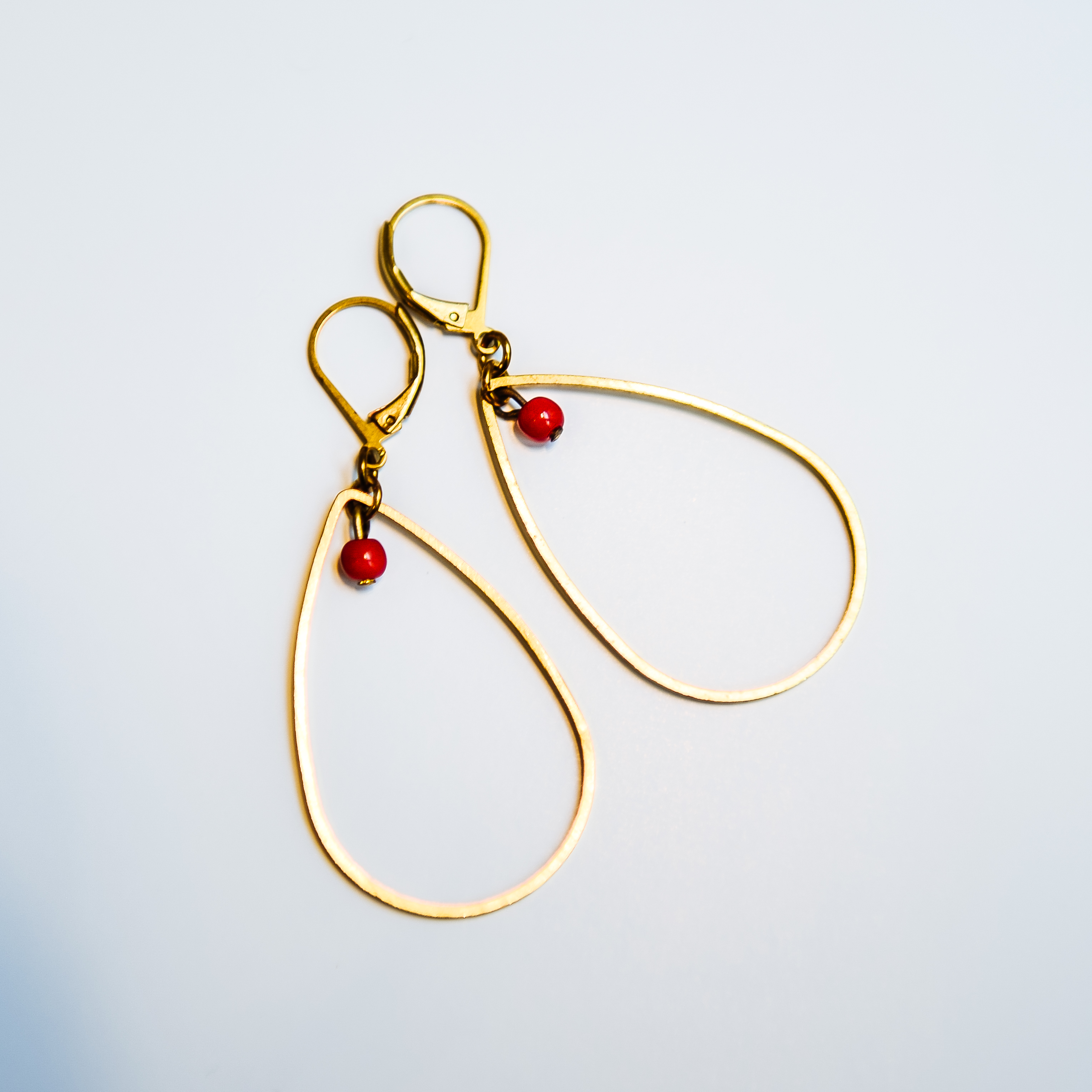 Boucles d'oreilles EOLE losange laiton doré et sa perle ronde en verre de couleur. Fermoir laiton. Existe en plusieurs coloris 